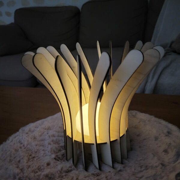 Lampe en bois Luma, composée de plusieurs lamelle et d'un led en son centre ppour illuminer. Posée sur une table basse