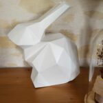 Grand lapin en 3D, style low poly, posé sur un buffet en décoration