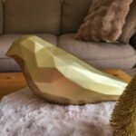 Grand oiseau en 3D, style low poly et peint en or. Photo prise sur une table à manger