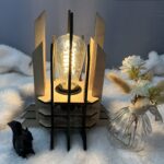 Lampe Luxor en bois moderne. Elle est réversible avec ses deux couleurs noir et blanc. La lampe est posée sur une nappe en velour avev un écureuil en 3D et un pot de fleur à côté