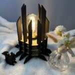 Lampe Luxor en bois moderne. Elle est réversible avec ses deux couleurs noir et blanc. La lampe est posée sur une nappe en velour avev un écureuil en 3D et un pot de fleur à côté