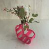 Décoration coeur "Adoration" en bois en rose. C'est un coeur qui accueil en son centre un petit vase pour y mettre des fleurs. Le coeur est un peu décalé et en plan large.