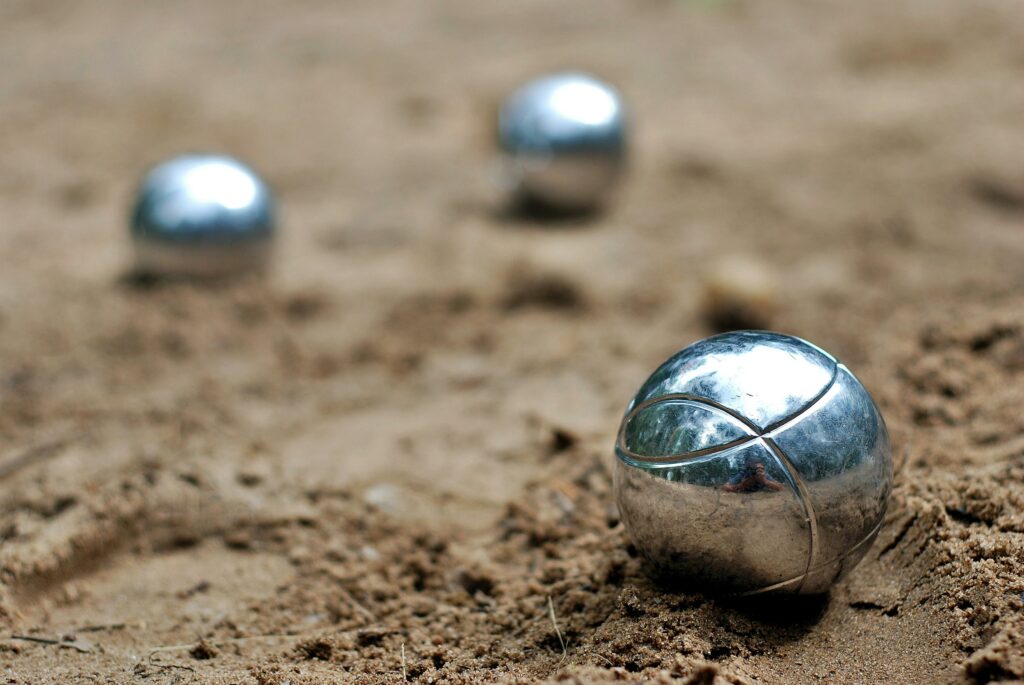 3 boules de pétanque sur de la terre. Adopter un compteur de point de pétanque pour faciliter le comptage de points de pétanque