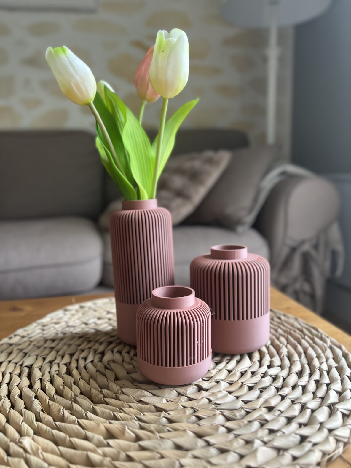 3 vases Solea emboîtables mauve sur un tapis en bois. 3 vases de tailles différentes, le plus grand contient des tulipes blanches