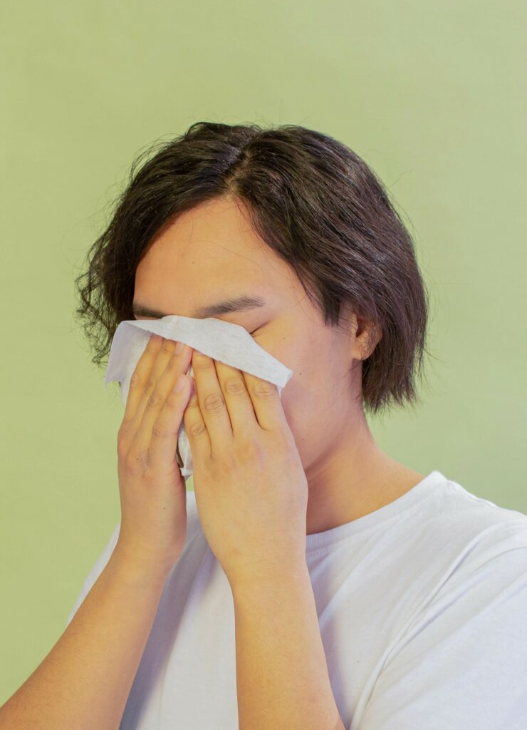 Jeune homme avec une lingette humide qui se frotte le visage pour se rafraichir efficacement pendant une période de forte chaleur