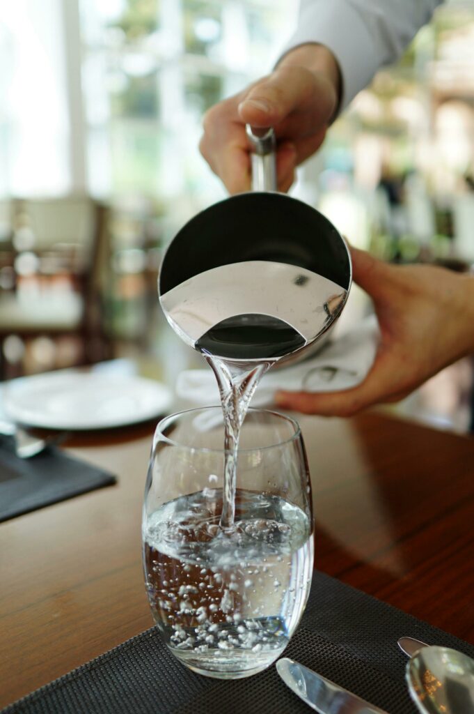 Pichet d'au qui verse de l'eau dans un verre. Cette astuce pour se rafraichir est la meilleur sur le moment. Retrouvez la suite de nos 7 astuces